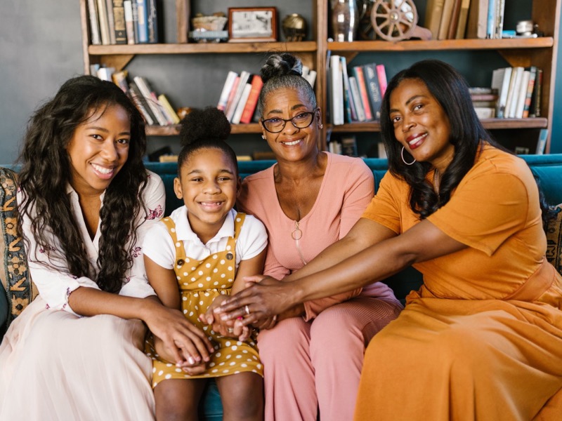 Four generations of a family smiling together on a sofa